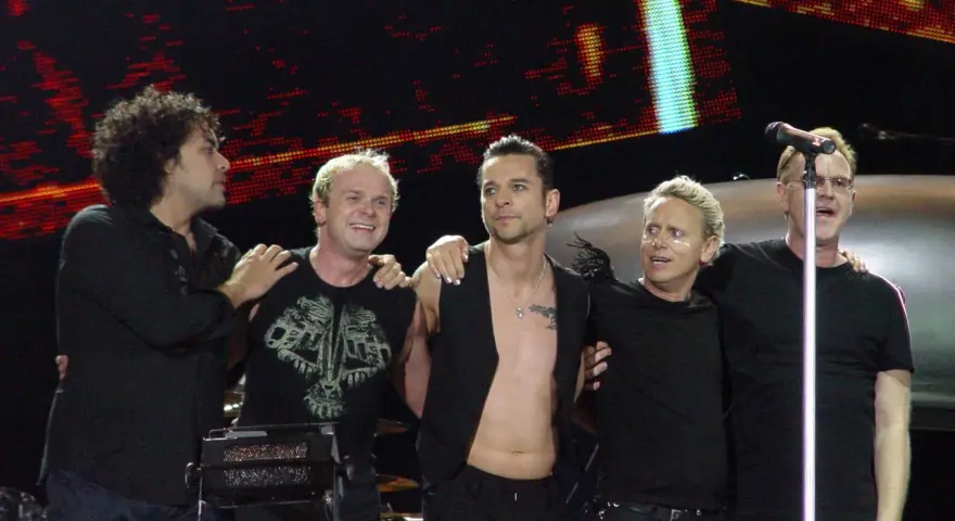 Les membres de Depeche Mode sur scène, souriants et complices, profitent de l'instant.