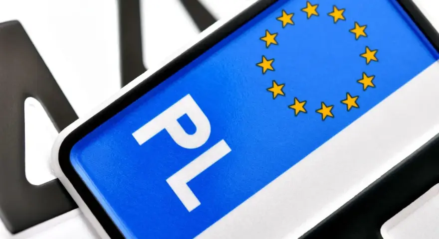 Zbliżenie na polskie tablice rejestracyjne z symbolem UE. Litery "PL" i gwiazdki na niebieskim tle.