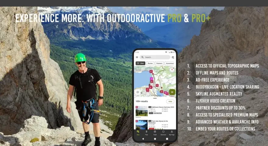 Escursionista sorridente in montagna, con smartphone che mostra l'app outdooractive gratis con mappe e percorsi.