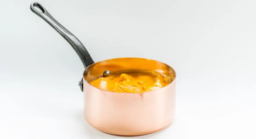 Cazo de cobre con puré de boniato cremoso y naranja, listo para servir.