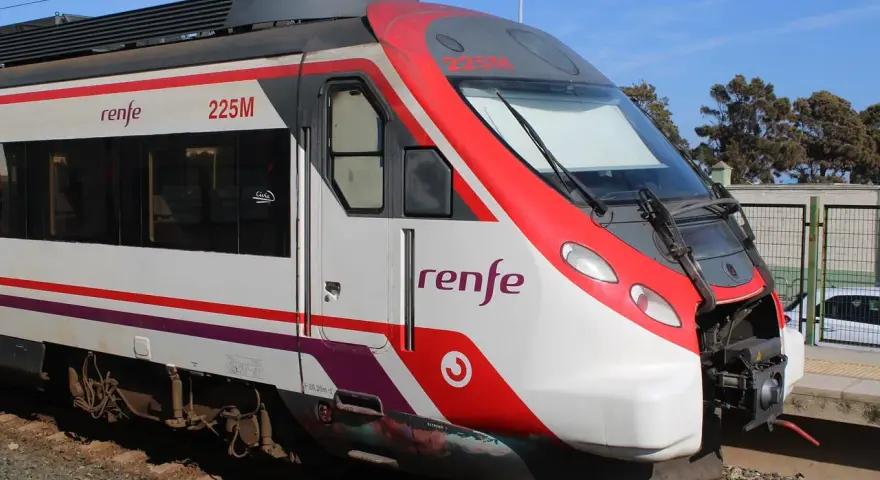 Czoło pociągu Renfe 225M z czerwonymi i białymi pasami, stojącego na torach.