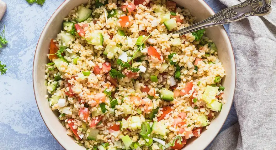 Frischer bulgur salat mit Tomaten, Gurken und Frühlingszwiebeln, garniert mit Petersilie.