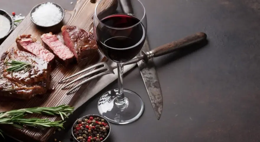 En saftig entrecote, perfekt tillagad, med ett glas rött vin. Kryddor och rosmarin fulländar upplevelsen.