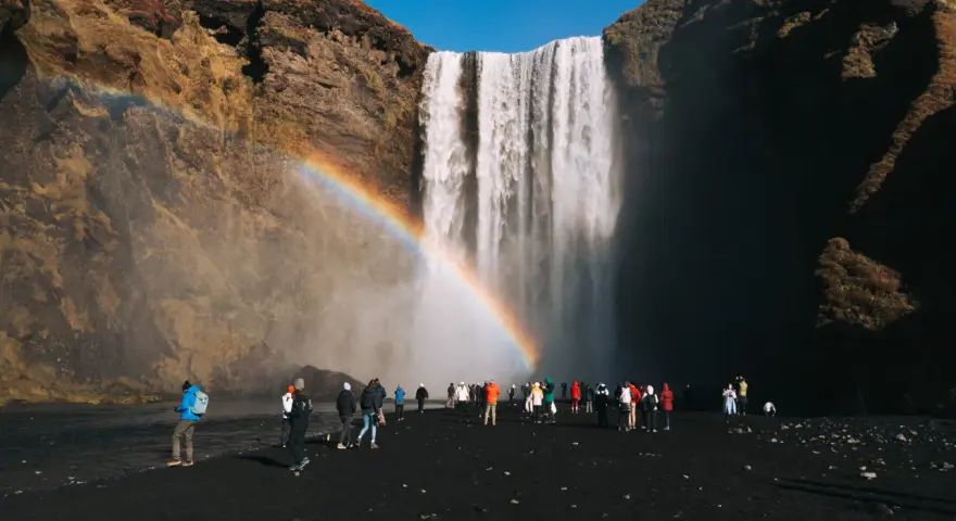 Turyści pod wodospadem Skógafoss na Islandii. Czy do Islandii trzeba mieć paszport? Tak, dla obywateli spoza strefy Schengen.
