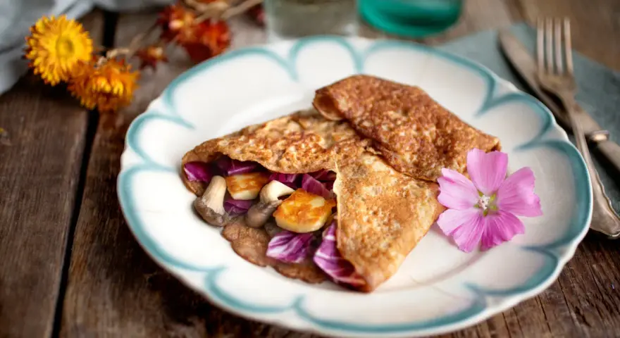 Matiga pannkakor fyllda med svamp, halloumi och rödkål, dekorerade med en rosa blomma.