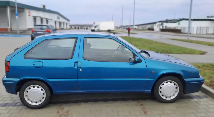Błękitny Citroen ZX stoi na parkingu.