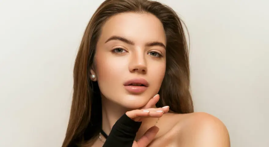 Delikatny makijaż nude podkreśla naturalne piękno młodej kobiety. Jej skóra lśni subtelnym blaskiem, a usta kuszą delikatnym kolorem.