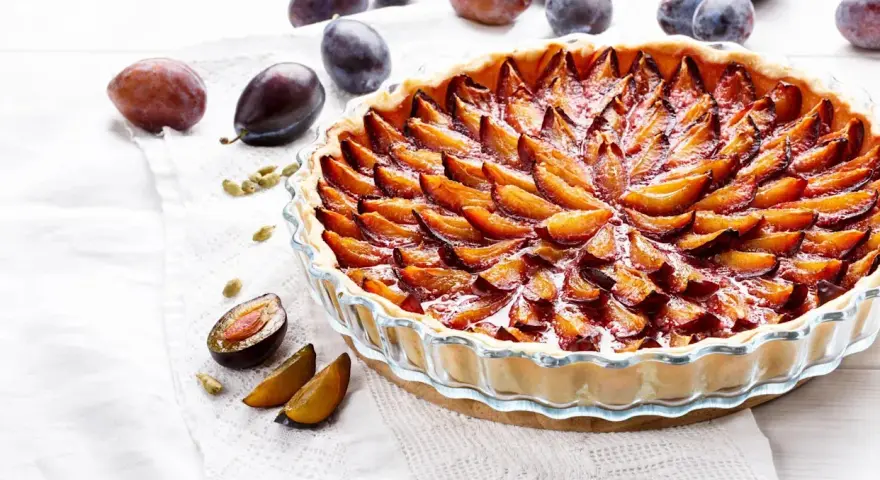 Une délicieuse tarte aux prunes, garnie de fruits frais et dorés, prête à être dégustée.