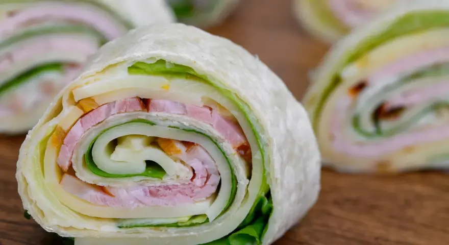 Szybkie przekąski z tortilli na zimno: zawinięte placki z szynką, serem i sałatą. Idealne na lunch lub imprezę.
