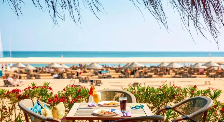 Stolik z jedzeniem i napojami na plaży, w tle morze i leżaki. Tui Magic Life Jacaranda - idealne miejsce na wakacje.