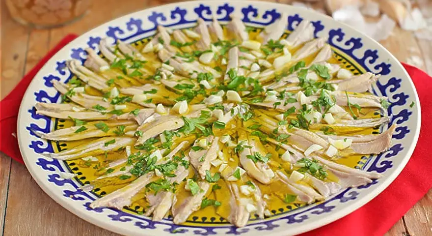 Boquerones en vinagre, un plato fresco y sabroso, servido en una fuente decorada con perejil y ajo picado.