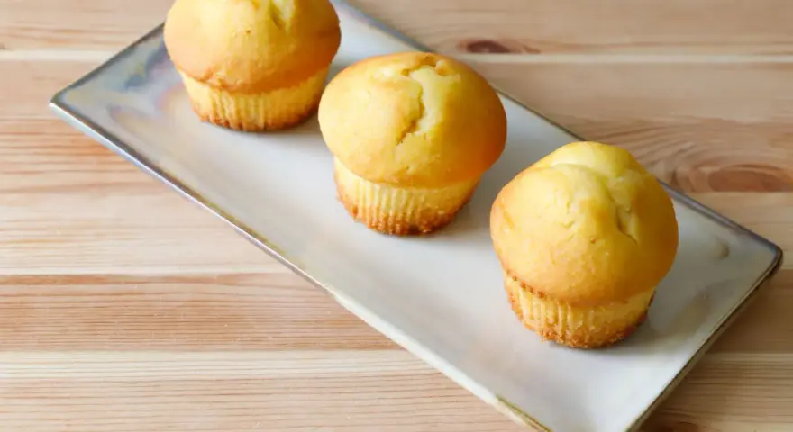 Tre soffici muffin allo yogurt dorati, pronti per essere gustati su un piatto rettangolare.
