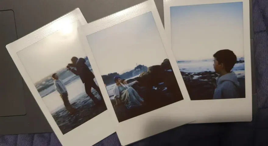 Trzy zdjęcia jak z Instax: chłopiec na plaży, para na skałach i chłopiec patrzący na morze.