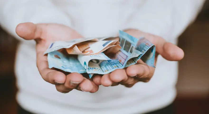 Dłonie trzymające banknoty euro, symbolizujące opłatę za pełnomocnictwo.