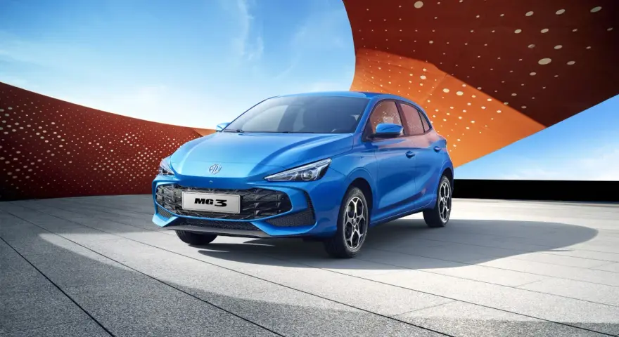 Niebieski MG3 Hybrid stoi na tle nowoczesnej architektury i błękitnego nieba.
