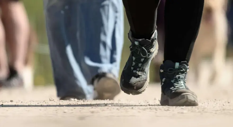Wanderstiefel in Aktion, die den Boden aufwirbeln. Die boot geschwindigkeit ist spürbar, während die Wanderer voranschreiten.