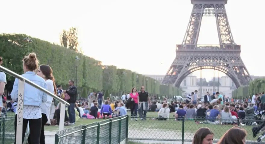 Gente disfrutando de un día soleado en París, con la Torre Eiffel de fondo. Un momento perfecto para la bise en France.