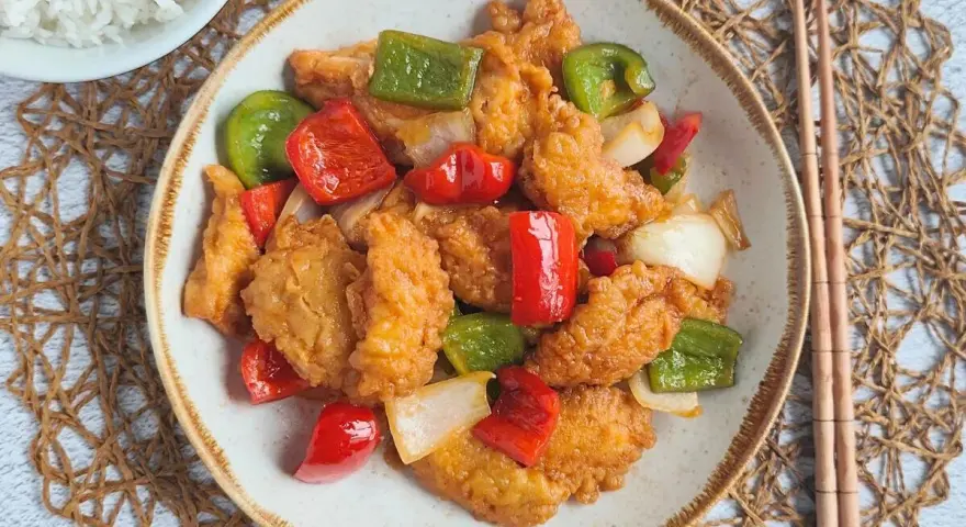 Delicioso pollo agridulce con pimientos rojos y verdes, y cebolla. Un plato vibrante y sabroso, listo para disfrutar.