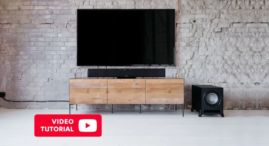 Schwarzer Subwoofer neben einem TV-Möbel. Hier erfahren Sie mehr über den subwoofer anschluss.