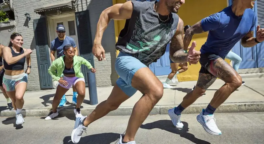 Grupa biegaczy w letnich strojach pokonuje miejską trasę. To inspiracja, jak przygotować się do maratonu, czerpiąc radość z ruchu.