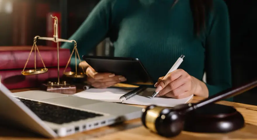 Prawniczka analizuje dokumenty, pilnując, by nie przegapić ostatniego przedawnienia długu. Na biurku waga sprawiedliwości, laptop i młotek sędziowski.
