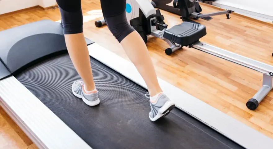 Gambe di donna che cammina su un tapirulan, in allenamento per la gravidanza.