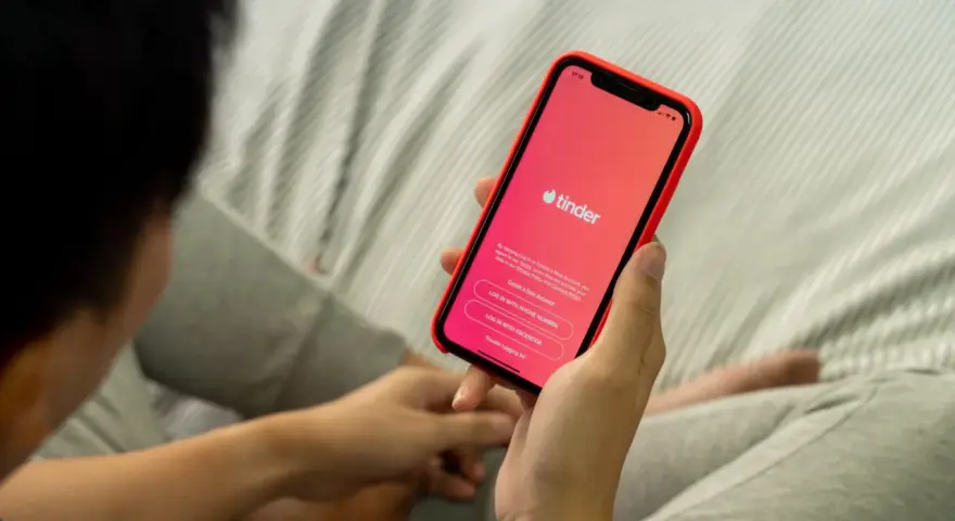 Osoba trzyma telefon z aplikacją Tinder. Zastanawiasz się, czy warto założyć Tindera? Może to początek nowej znajomości.