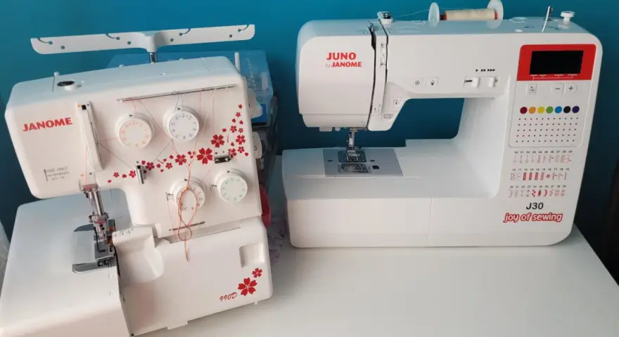 Dwie maszyny do szycia: biały owerlok Janome 990d z czerwonymi kwiatami i biała maszyna Juno by Janome J30.