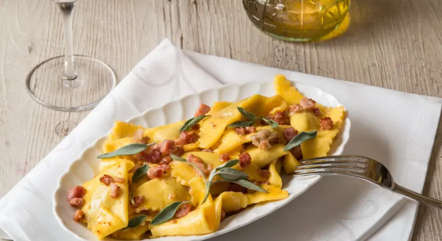 Piatto di casoncelli alla bergamasca conditi con burro, salvia e pancetta croccante.