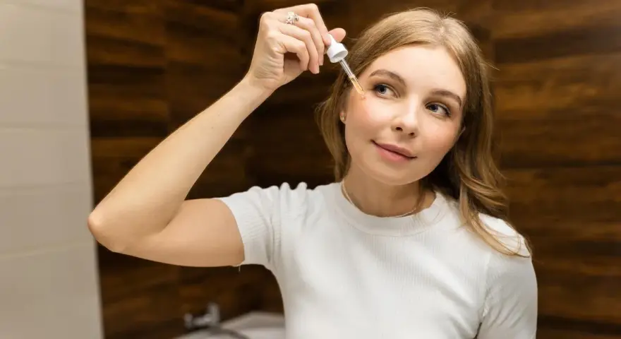 Donna applica siero viso con contagocce, concentrandosi sul giusto retinolo percentuale per la sua pelle.