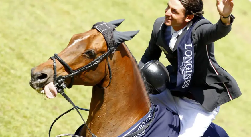 Un cavalier, Nino des Buissonnets, salue la foule depuis son cheval après une compétition.