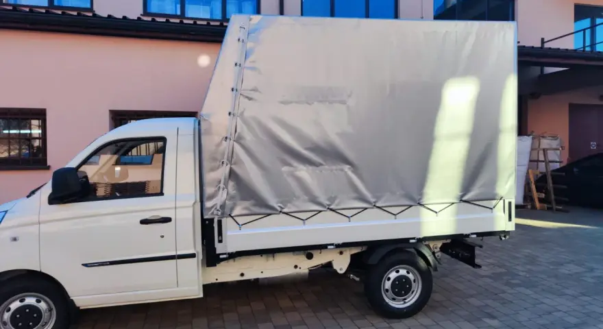 Biały samochód ciężarowy do 2,5 tony z plandeką gotowy do transportu towarów.