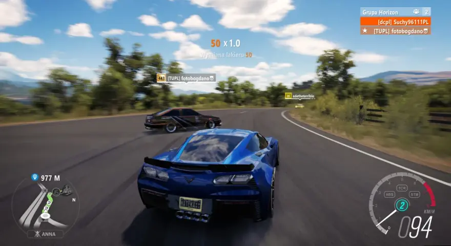 Wyścig w Horizon 3: niebieski Chevrolet Corvette ściga się z innymi autami na krętej drodze.
