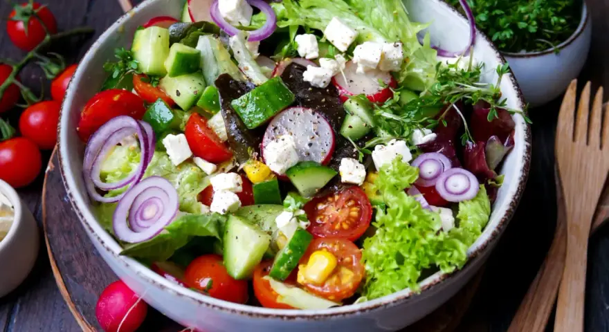 Ein bunter gemischter Salat mit Tomaten, Gurken, Radieschen, Zwiebeln und Feta.