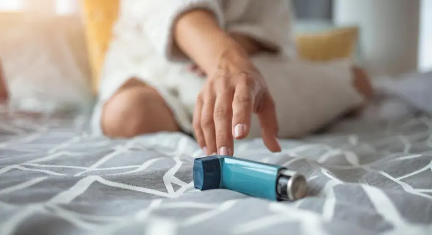 Mano tesa verso un inalatore blu, un aiuto per respirare. Il foster spray è pronto all'uso.