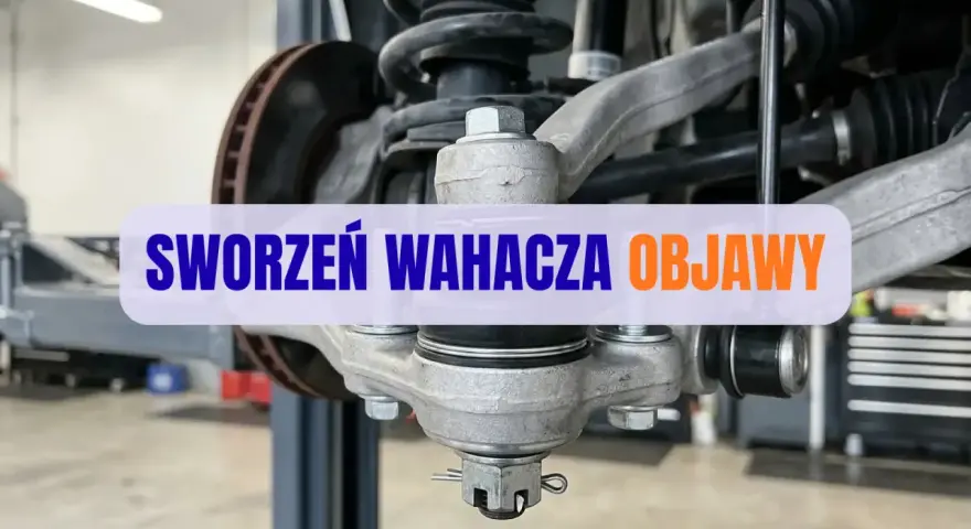 Widok na zawieszenie samochodu z widocznym sworzniem wahacza. Napis na zdjęciu informuje o objawach zużycia sworznia.