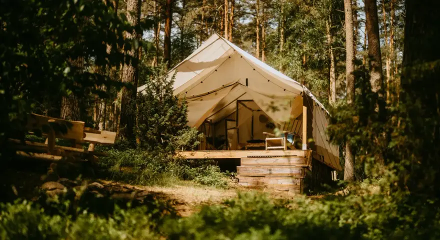 Namiot na Mazurach, otoczony lasem. Drewniana ławka i taras zapraszają do odpoczynku. Idealne miejsce na mazury pod namiot.