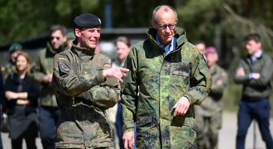 Dwóch mężczyzn w mundurach wojskowych, jeden z flagą Polski, drugi z napisem "MERZ" (Niemcy).