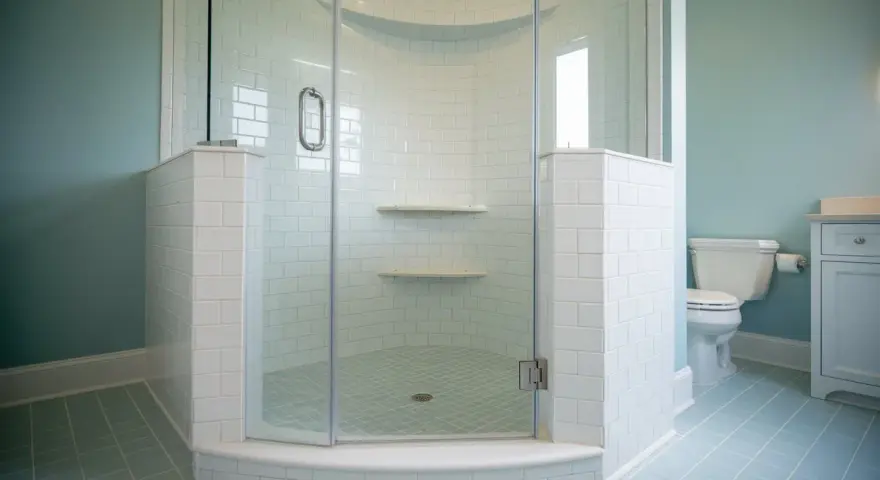 Salle de bain avec carrelage bleu pâle et une douche d'angle. Ce receveur de douche à éviter, avec ses étagères peu pratiques, est un cauchemar à nettoyer.