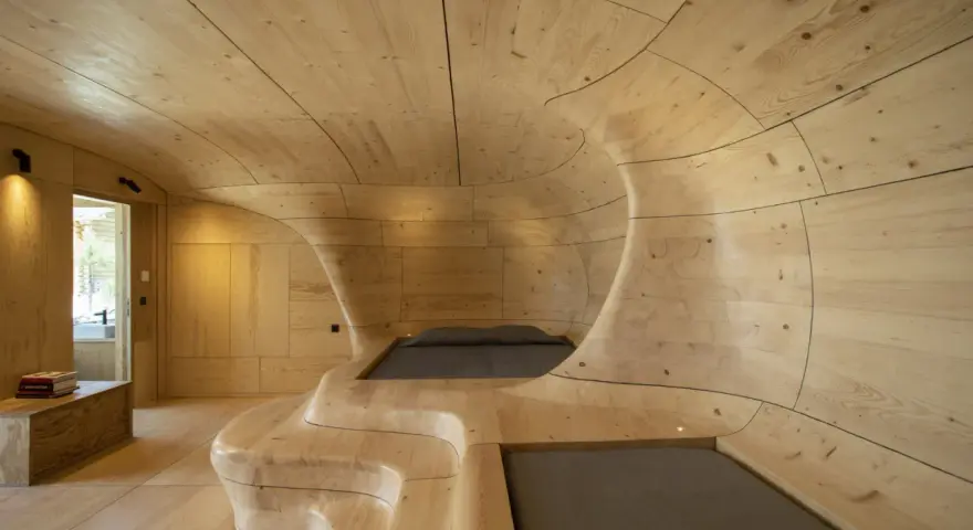 Interior de una casa cueva con paredes y techo de madera curvada, creando un espacio orgánico y acogedor.