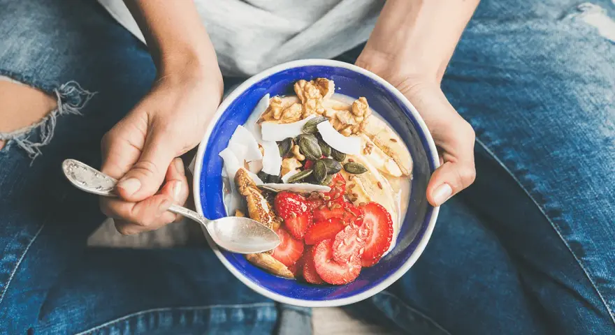 Un bol coloré de fruits, noix et graines, parfait pour une collation après sport.