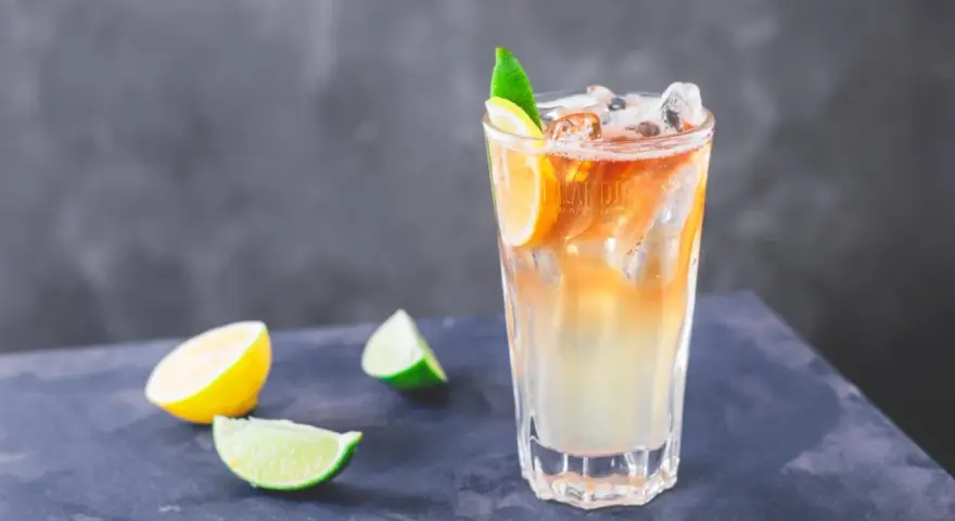 Orzeźwiający drink Long Island Iced Tea z plasterkami cytryny i limonki, idealny na upalne dni.
