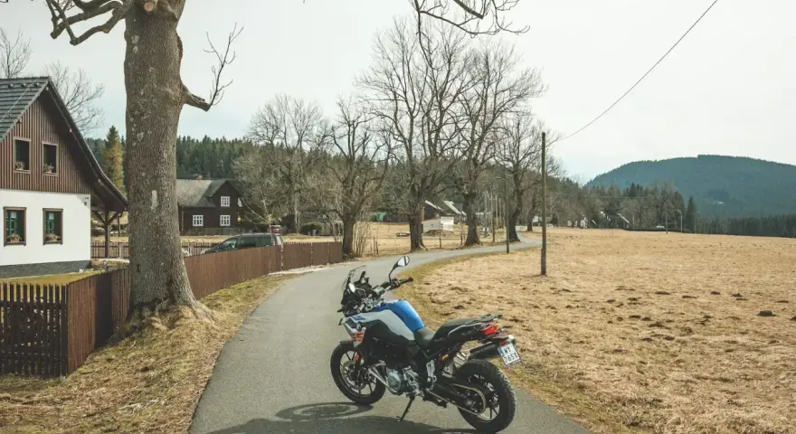 Motocykl czeka na jednodniowy wypad motocyklowy. W tle wiejskie domki i puste pola.