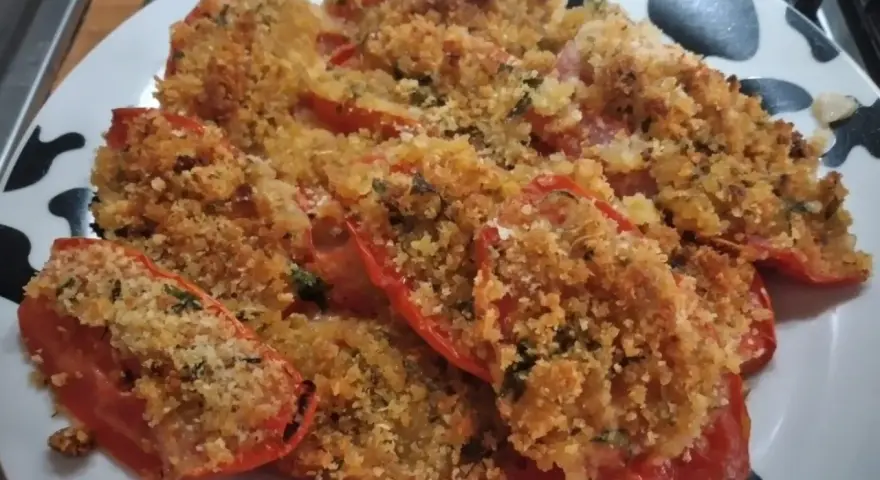 Pomodori gratinati al forno, un piatto semplice e gustoso, con una croccante panatura dorata e erbe aromatiche.