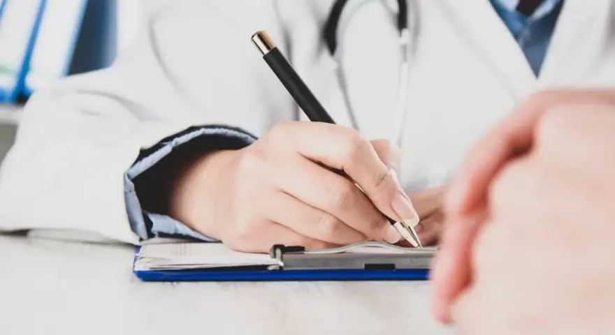 Lekarz pisze receptę, zastanawiając się, czy zwolnienie od psychiatry zostaje w papierach.