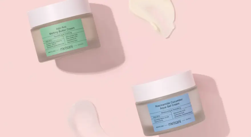 Due barattoli di crema viso Meisani, uno con niacinamide e burro, l'altro con niacinamide e cetriolo, su sfondo rosa. Perfetti per proteggere la pelle dal sole.