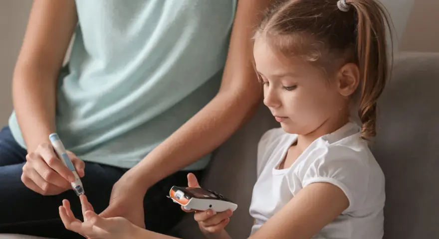 Mutter hilft Kind bei Blutzuckermessung. Ein wichtiger Teil im Leben mit diabetes kinder.