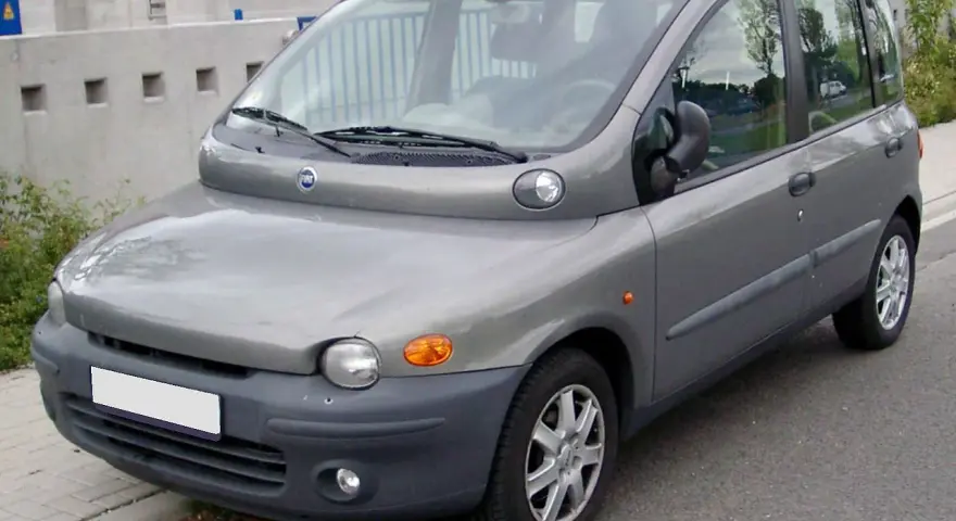 Szary Fiat Multipla, często uznawany za najbrzydsze auto na świecie, stoi na ulicy. Jego nietypowy kształt przyciąga wzrok.