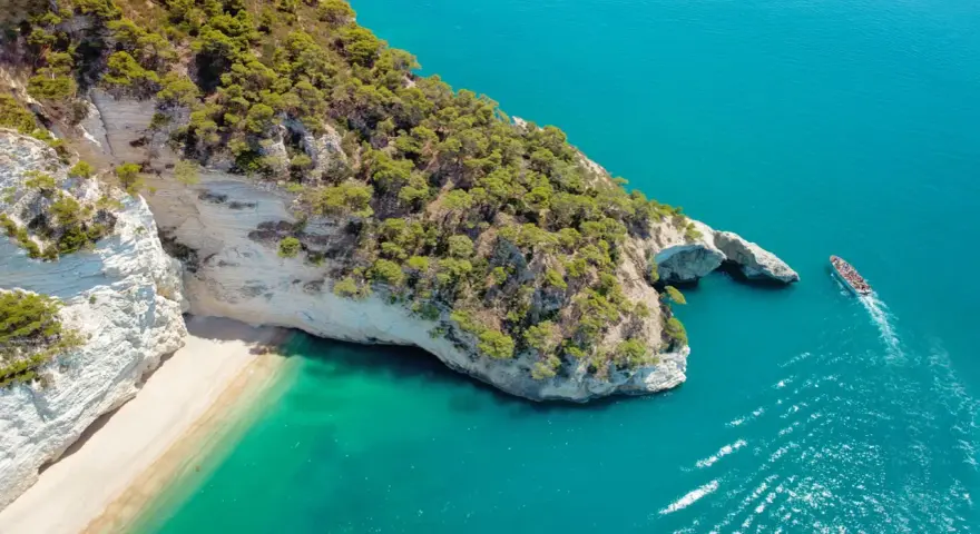Widok z lotu ptaka na skaliste wybrzeże Włoch z plażą i turkusową wodą.