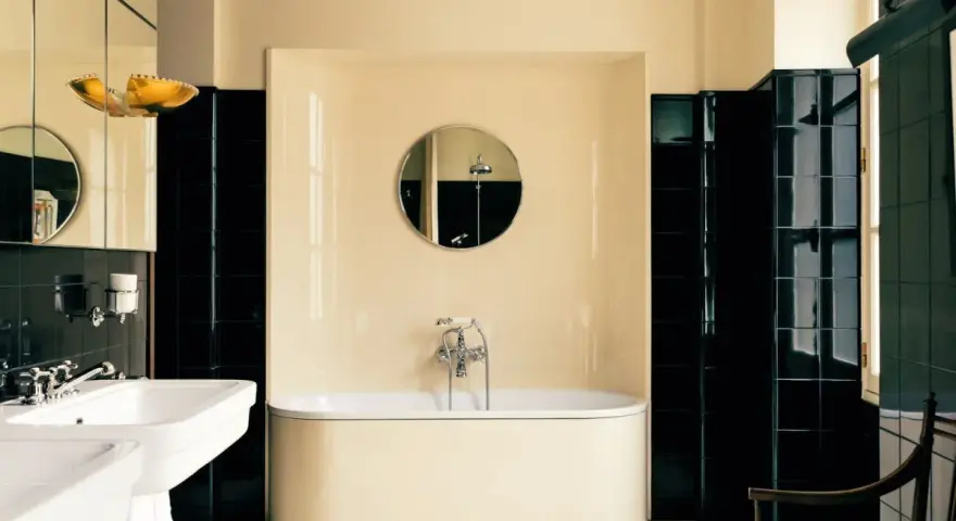 Élégante salle de bain noir et blanc avec baignoire îlot, lavabo double vasque et carrelage brillant.